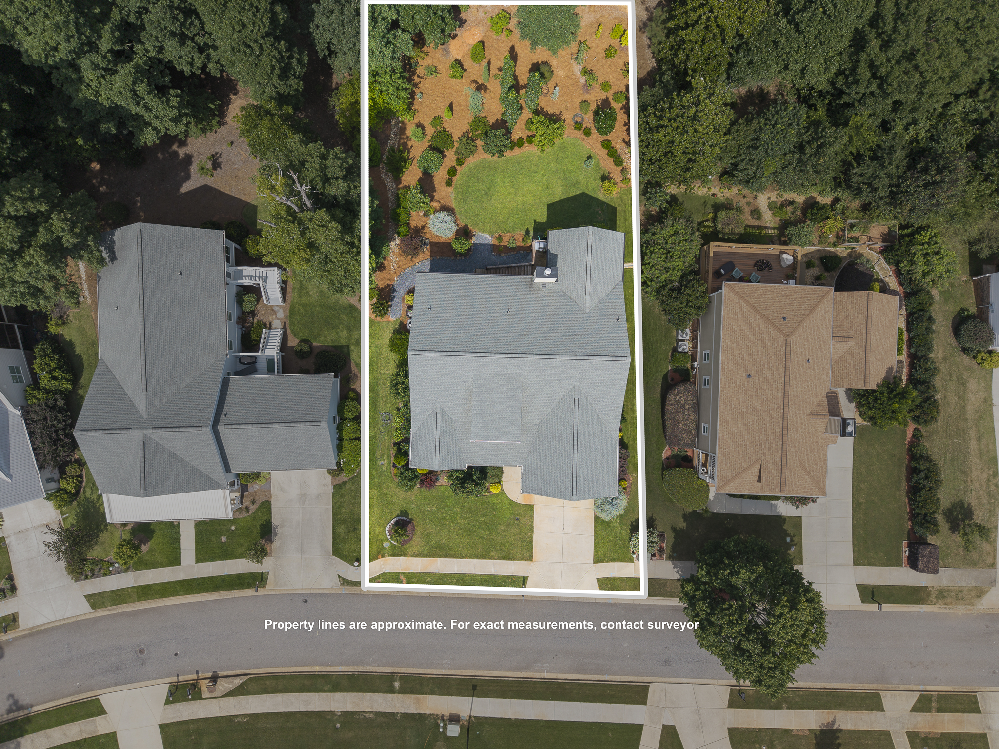 Aerial view of three houses with yards, showing property lines and surrounding trees.