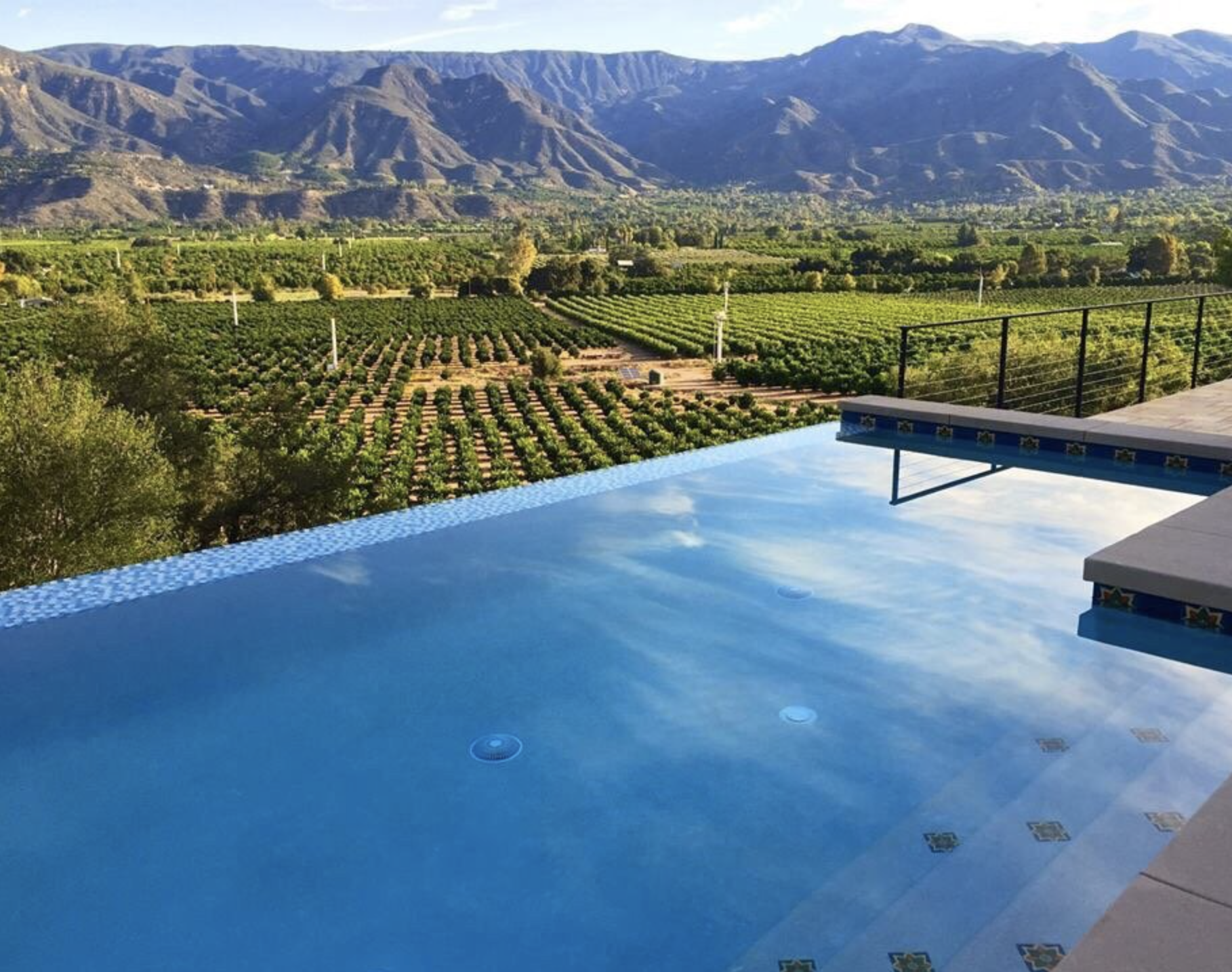 Infinity pool overlooking a lush green valley with mountains in the background