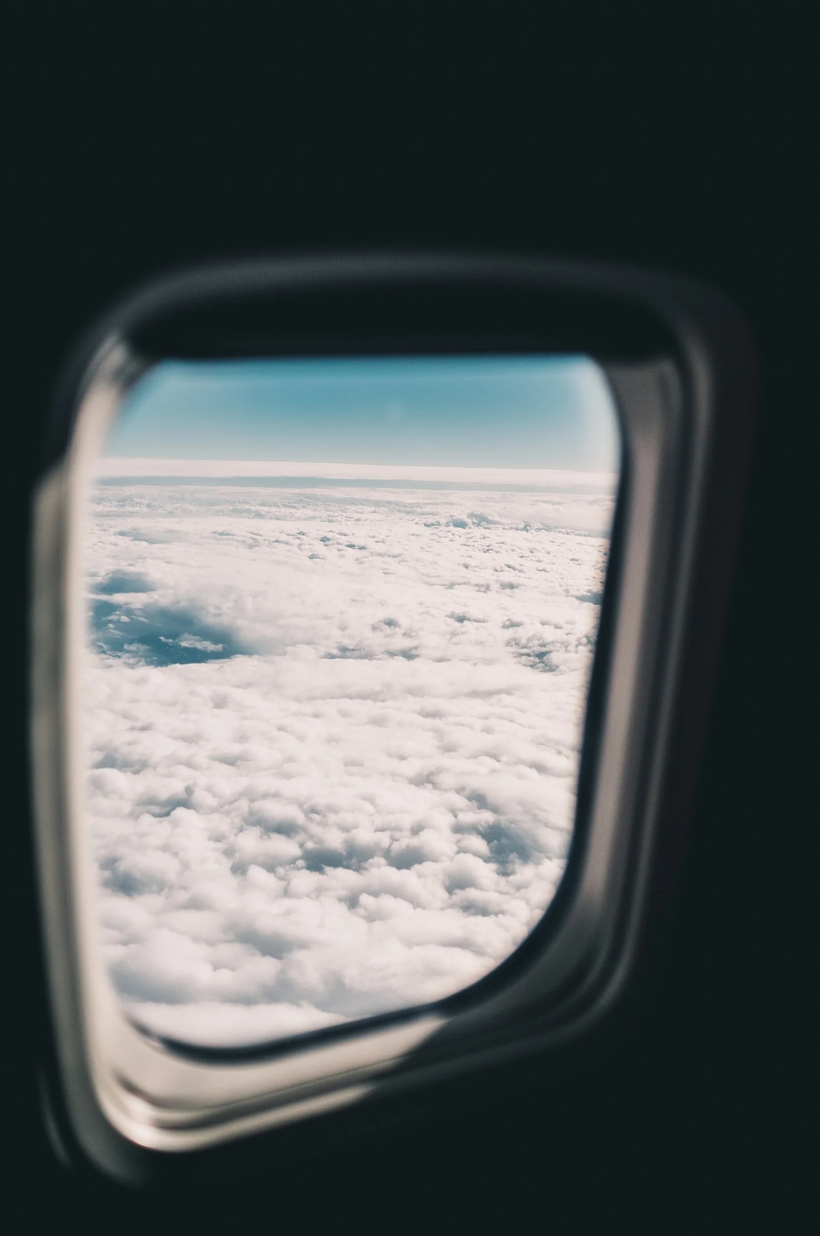 View of clouds and blue sky through airplane window.