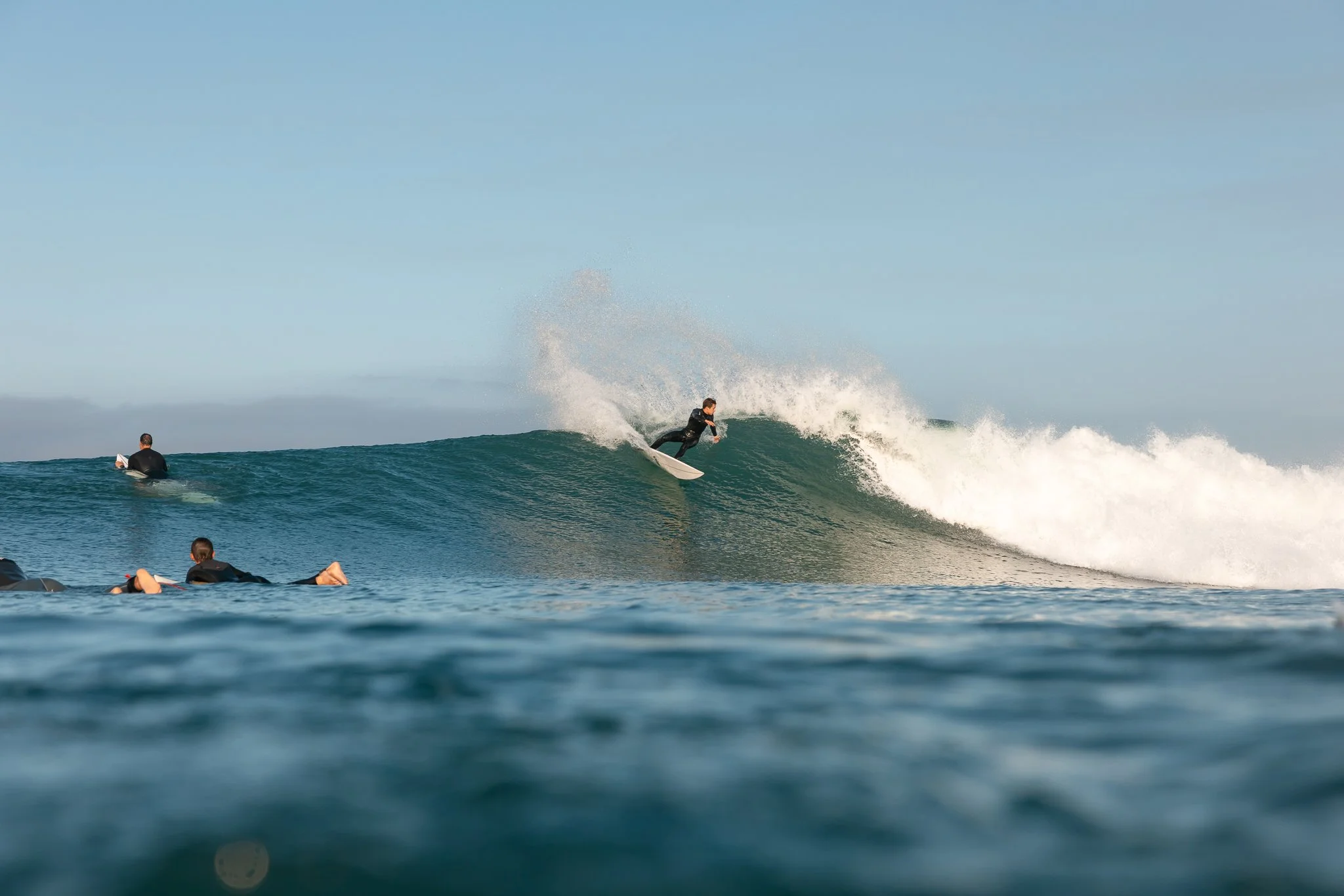A surfer riding a wave while others watch from the water.