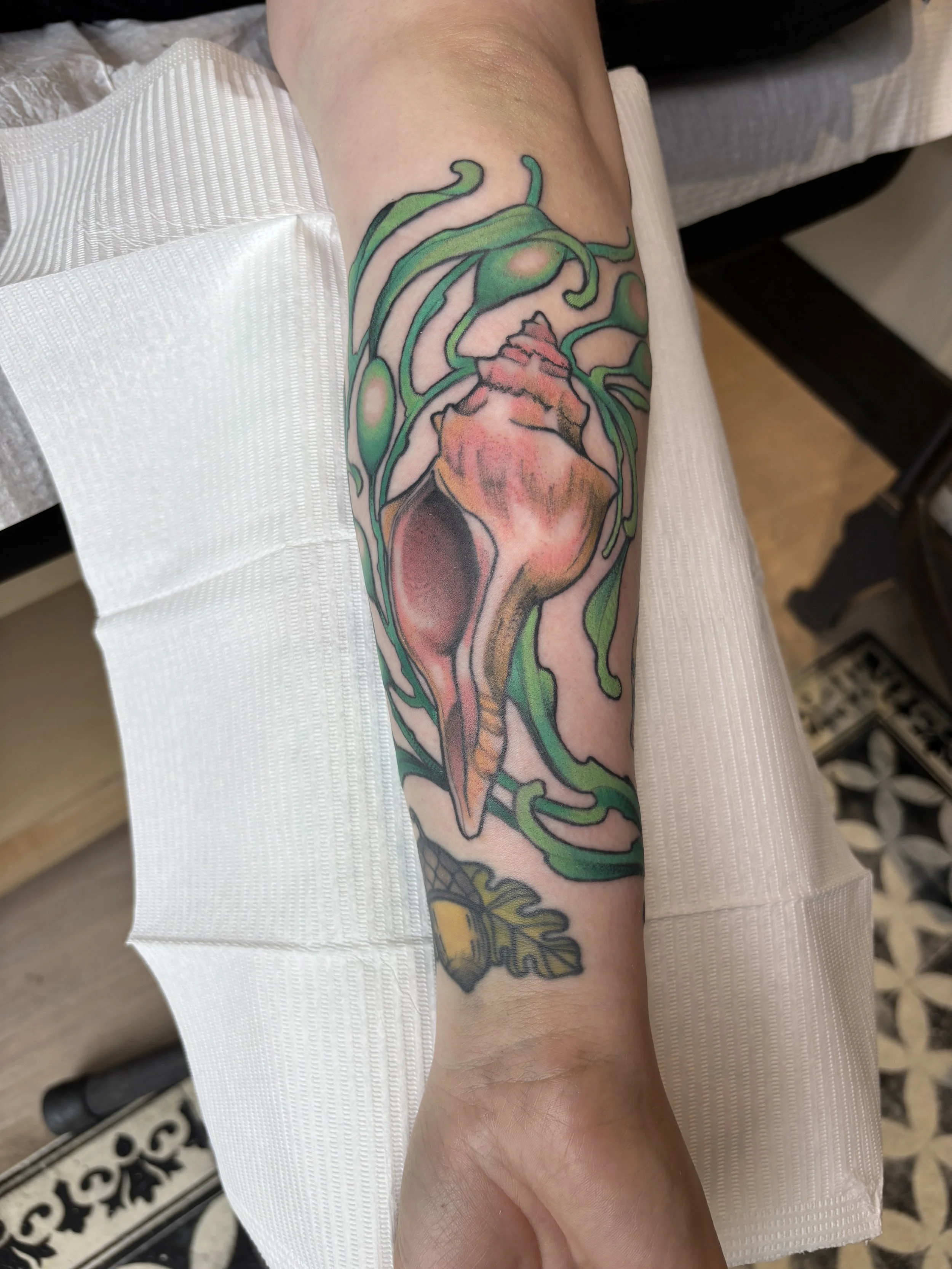 Colorful tattoo of a human heart with green swirls and a honey bee on the wrist area.