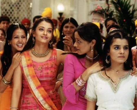 A colorful and energetic scene from the film Bride and Prejudice showing Aishwarya Rai as Lalita Bakshi and her sisters in traditional Indian attire, illustrating the global reach of Jane Austen’s story.