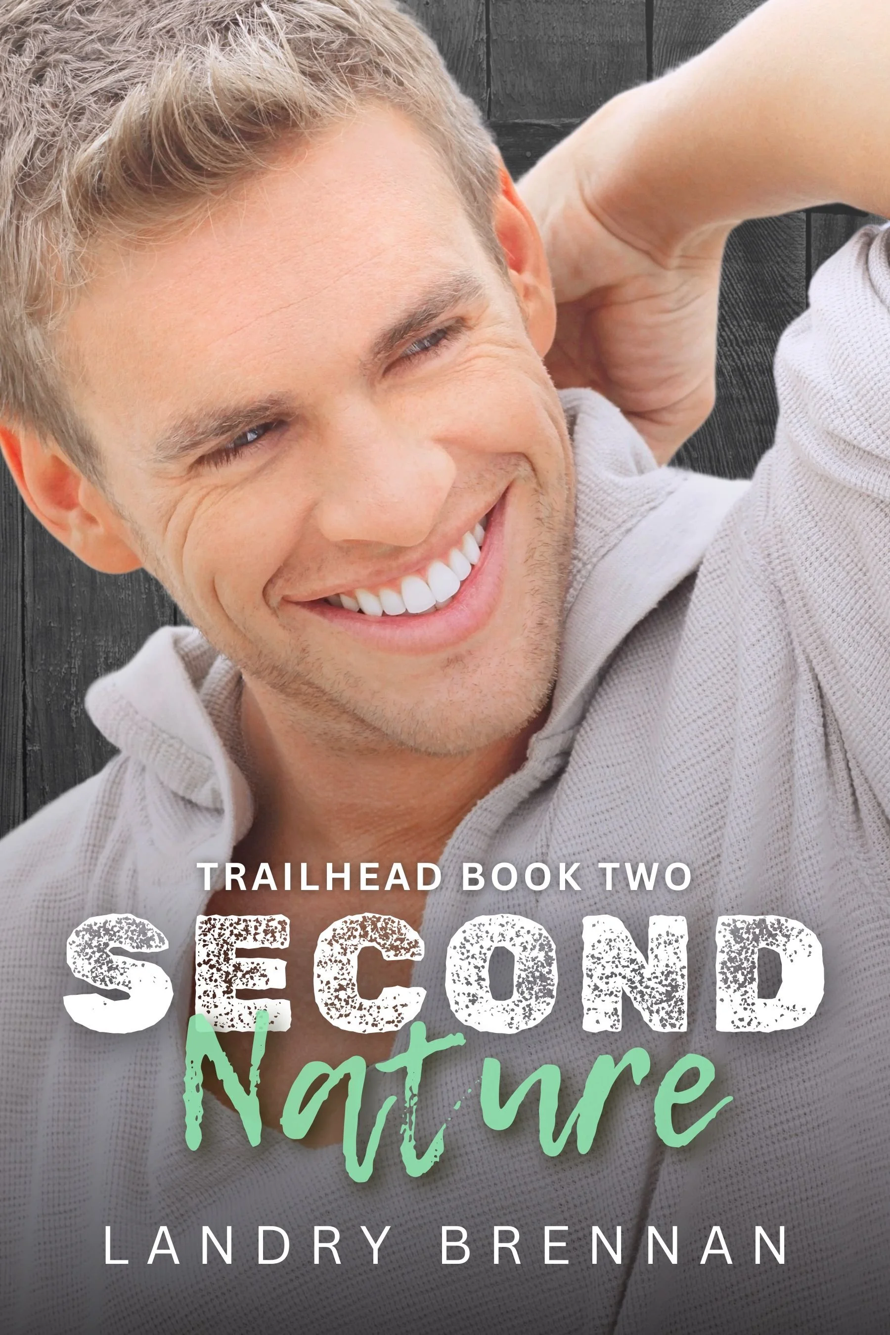 Close-up photo of a smiling man with light brown hair, wearing a light beige collared shirt. Background is a dark wooden surface. Overlaid text reads 'Trailhead Book Two', 'Sedona', and 'Landry Brennan'.