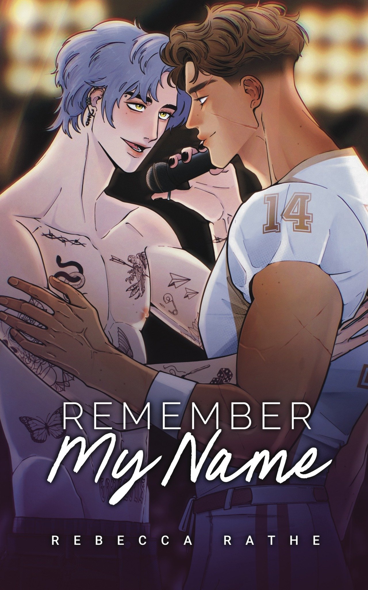 An animated illustration of two young men close together, one with purple hair and tattoos, the other with brown hair and wearing a football jersey with the number 14. They are touching foreheads and smiling, with the purple-haired man holding a microphone. The image has the text "Remember My Name" and "Rebecca Rathe" at the bottom.