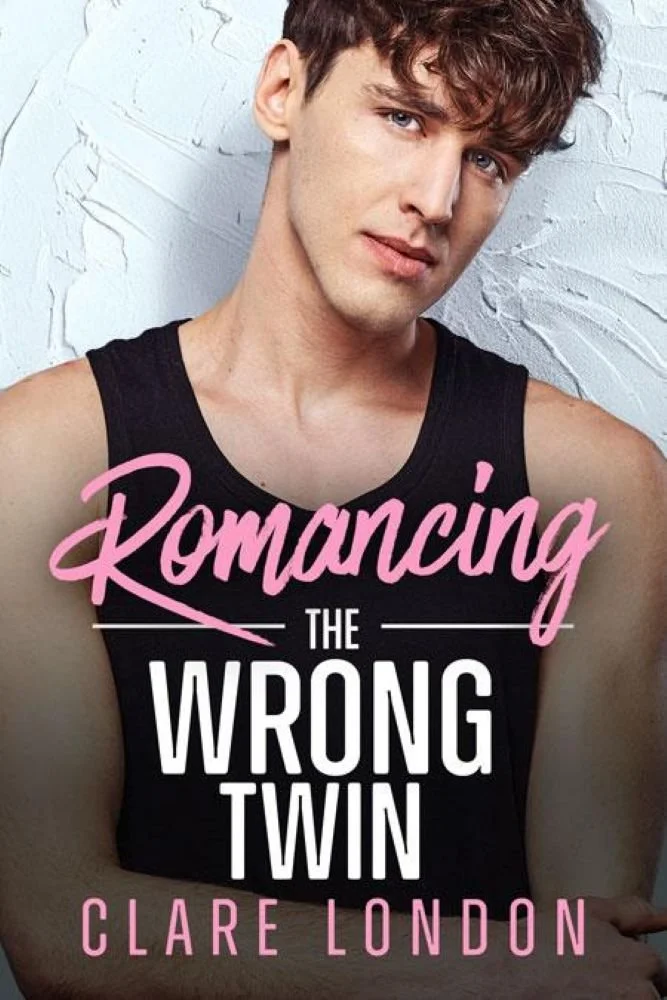 Book cover featuring a young man with brown curly hair, wearing a black tank top, against a white textured background, with the title 'Romancing the Wrong Twin' by Clare London in pink and white text.