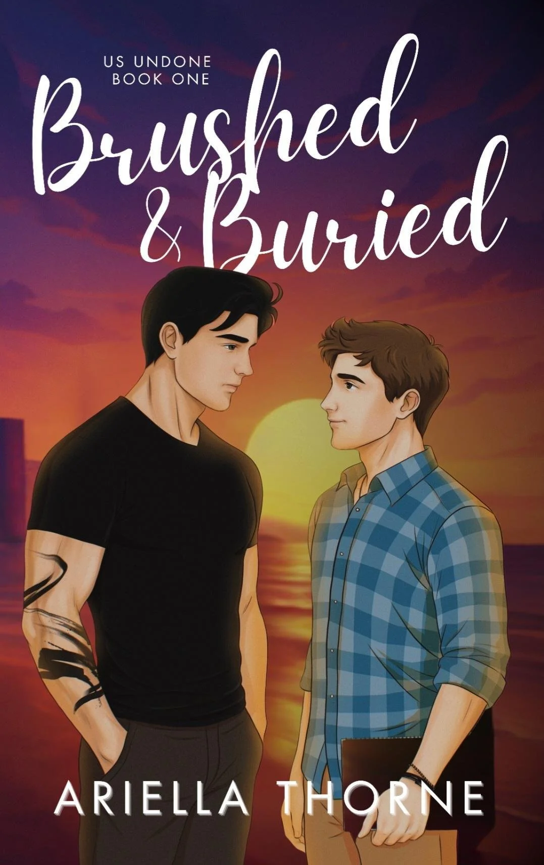 Cover of the book titled "Brushed & Buried" by Ariella Thorne, featuring two young men standing face to face, with a sunset over the water in the background.
