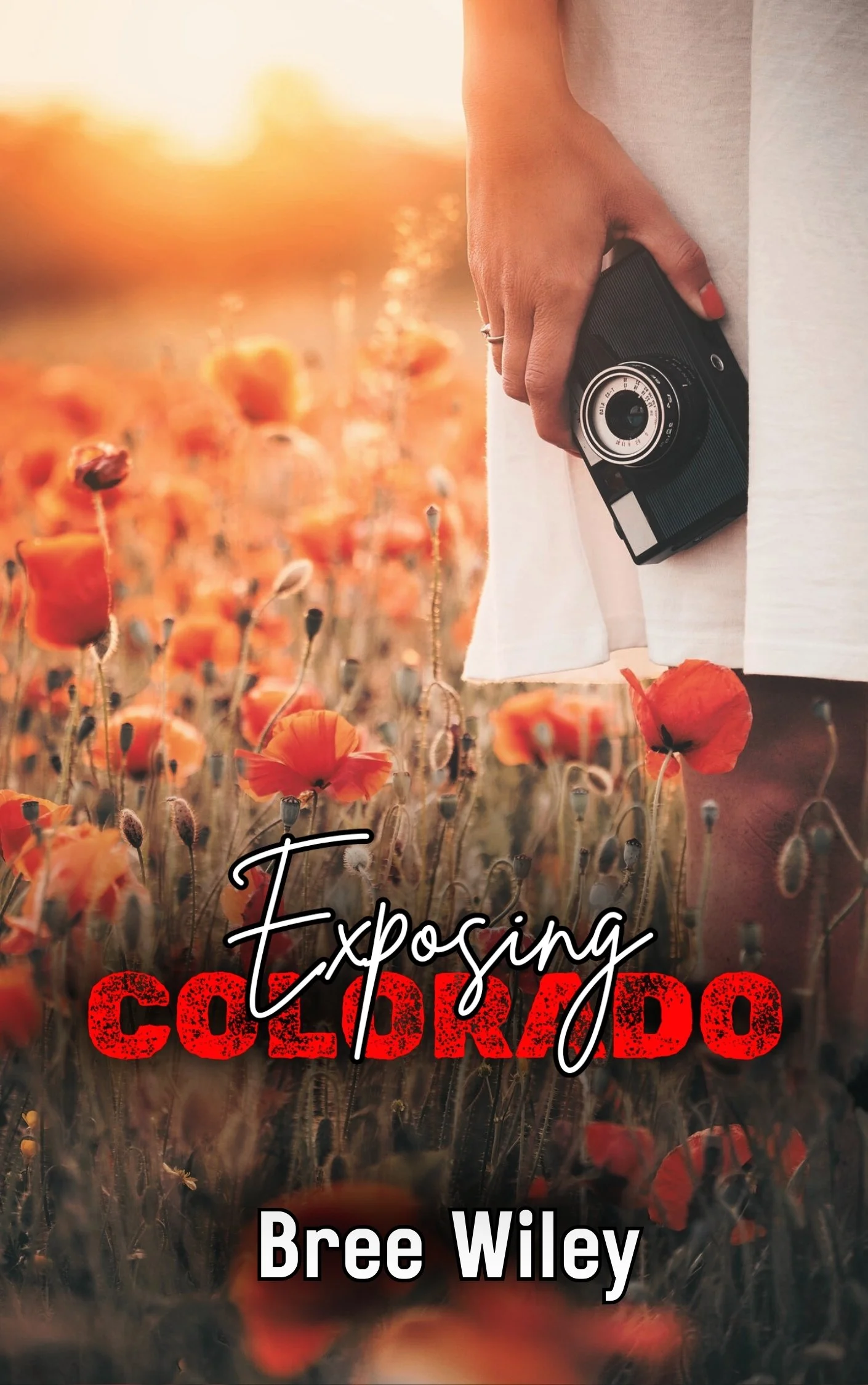 The cover of the book titled "Exposing Colorado" by Bree Wiley features a close-up photograph of a person holding a vintage camera in a field of orange poppies during sunset.