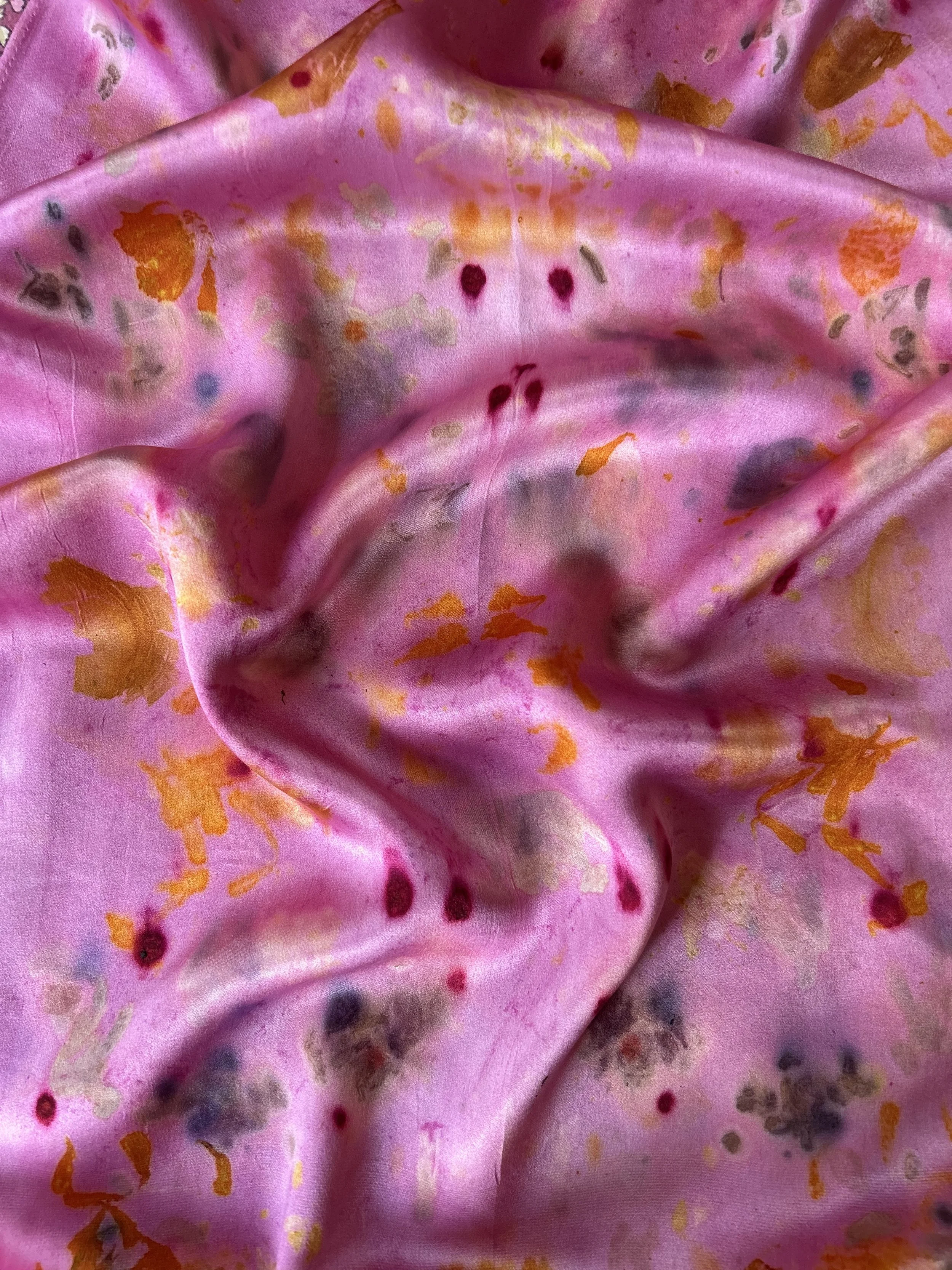 Fresh and dried flowers and leaves arranged on natural fabric for bundle dyeing, a botanical printing technique that transfers plant color and shape onto cloth through steam.