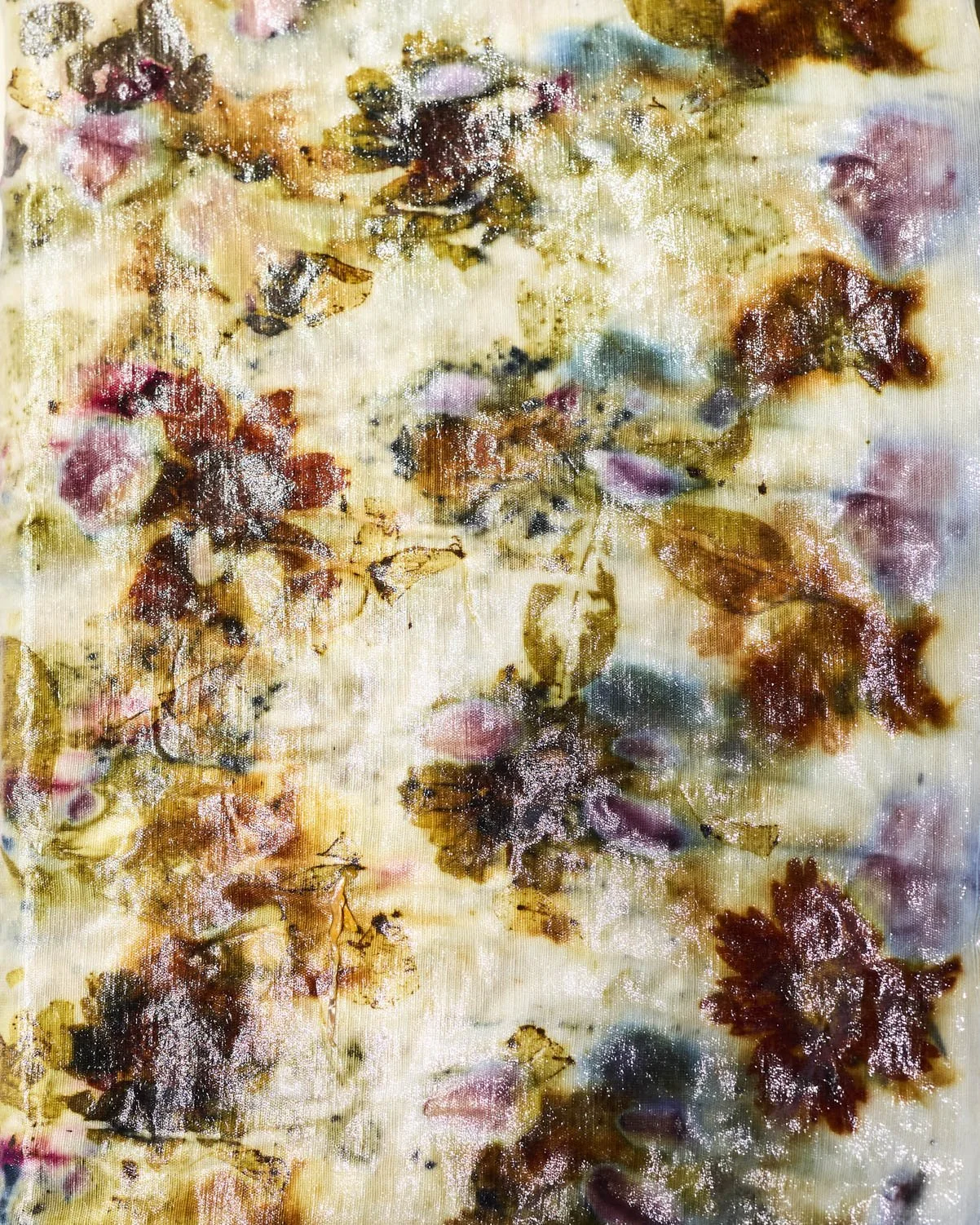 Fresh and dried flowers and leaves arranged on natural fabric for bundle dyeing, a botanical printing technique that transfers plant color and shape onto cloth through steam.
