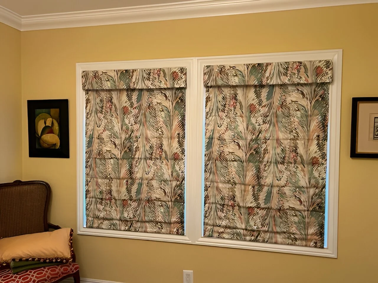 A living room with two large windows covered by patterned curtains featuring a floral design.
