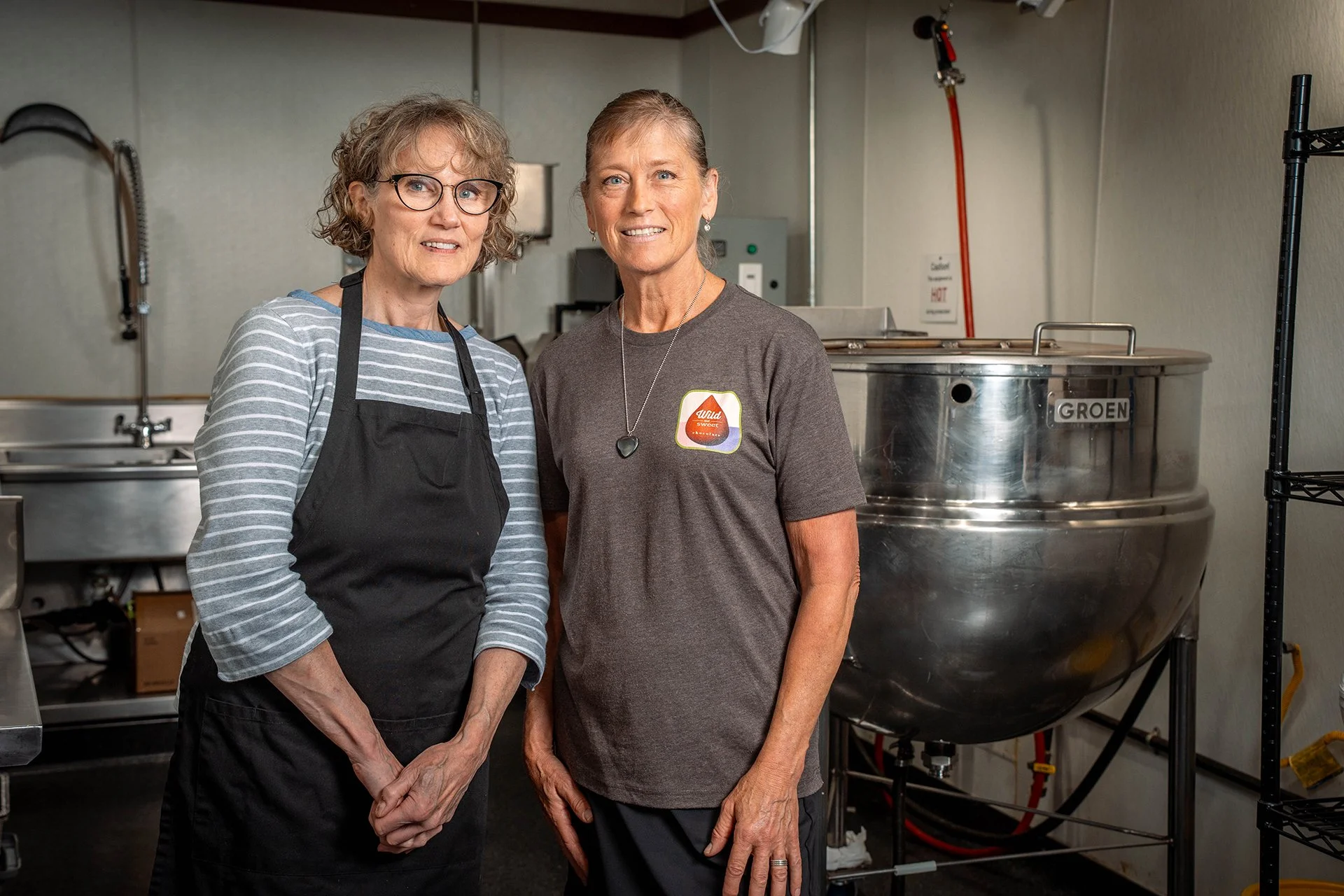 Two women stand side by side in an industrial kitchen for a portrait.
