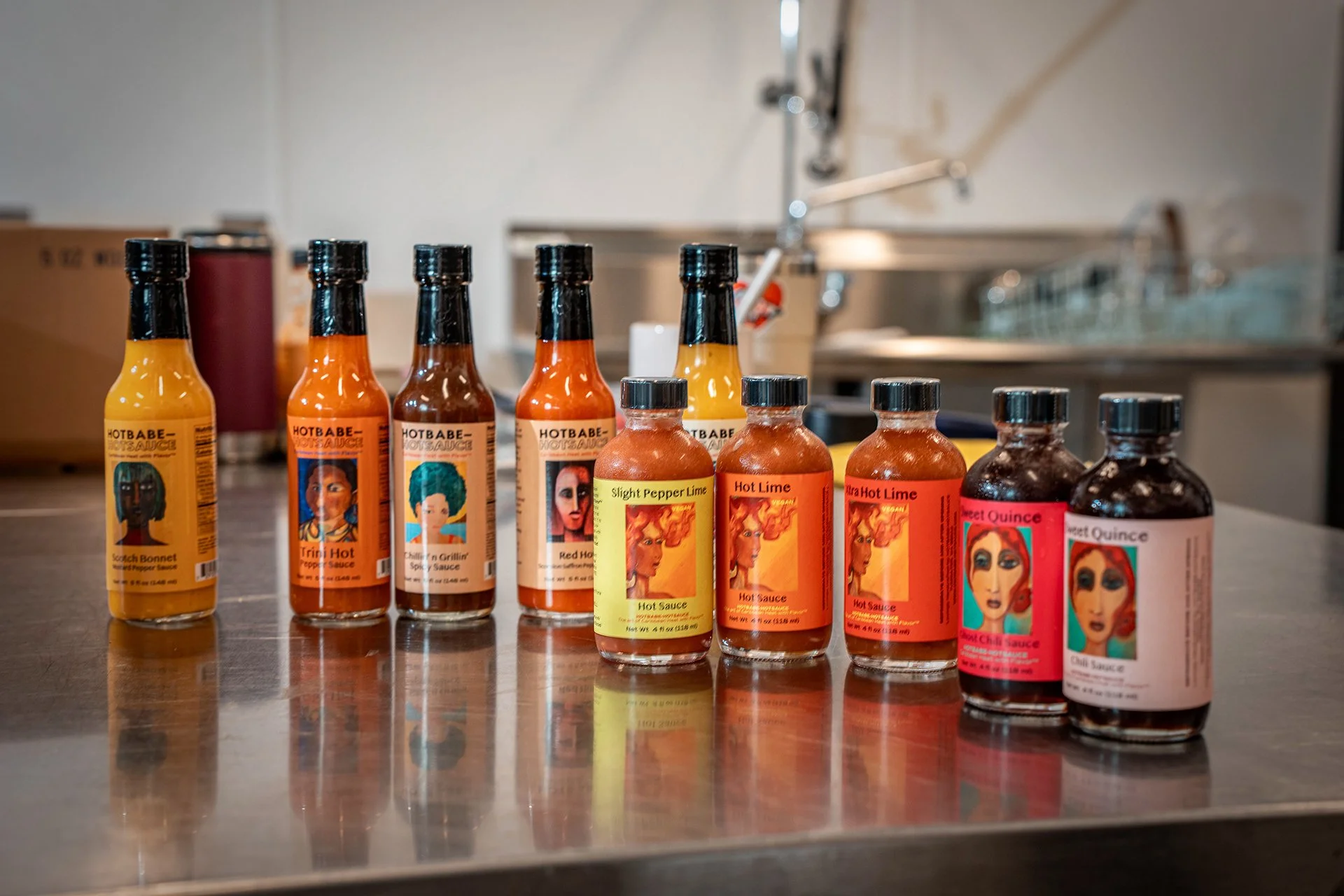 A selection of colorful hot sauce bottles displayed on a metal table.