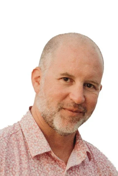 Headshot of a man with a speckled white and brown beard smiling at the camera
