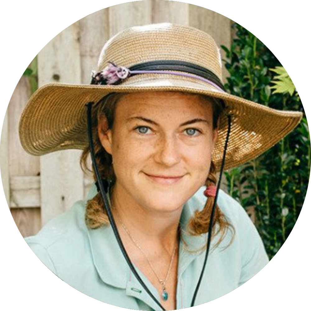 Circular portrait of Grace Wicks smiling with light eyes and hair in pigtails, wearing a wide-brimmed straw sun hat with a chin strap and a light green collared shirt.