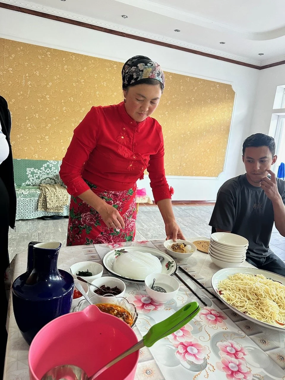  Our host, Eluma, walking us through how to make Ashlan-fu, a traditional Dungan noodle dish that has Chinese origins. Ashlan-fu starts with a base of starch noodles and lagman noodles and then is smothered in a sauce of vinegar, egg, meat, tomatoes,