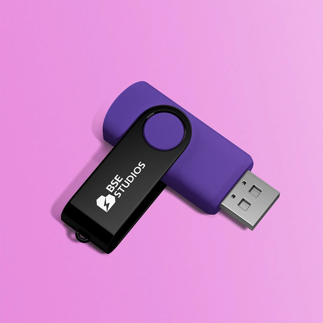 Una chiavetta USB nera con logo di BSE Studios e un supporto di silicone viola su sfondo rosa.