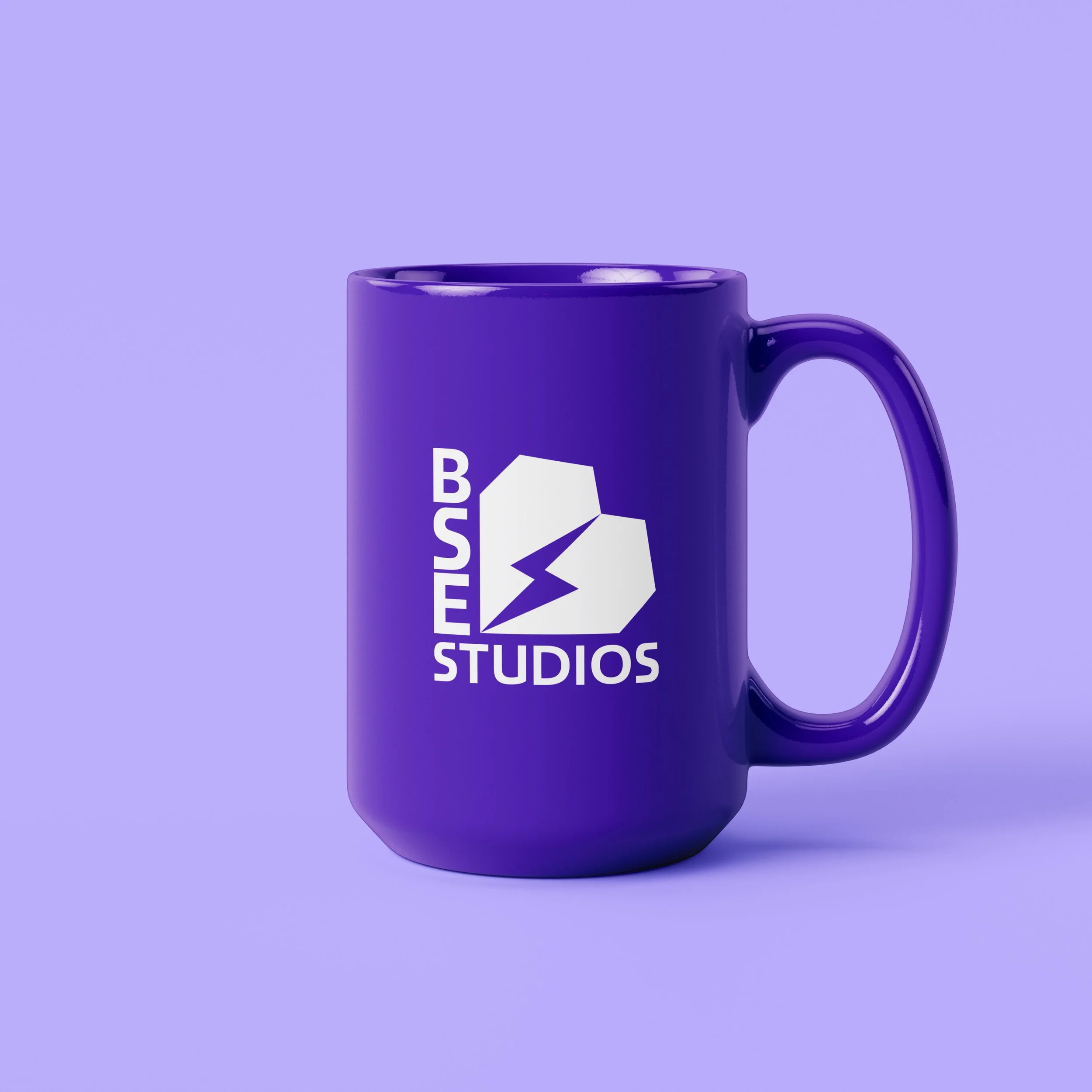 Una tazza viola con il logo di BST Studios, che mostra una forma di cuore con un fulmine al centro, e le parole 'BST STUDIOS'.