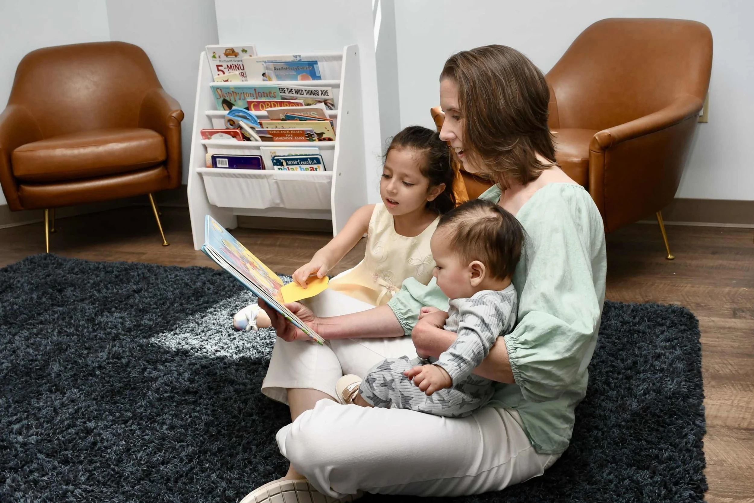 A man and a baby smiling at each other inside a house. They are both wearing matching T-shirts that read "Monkey's Uncle". The man is holding the baby up and the background includes wooden cabinets.