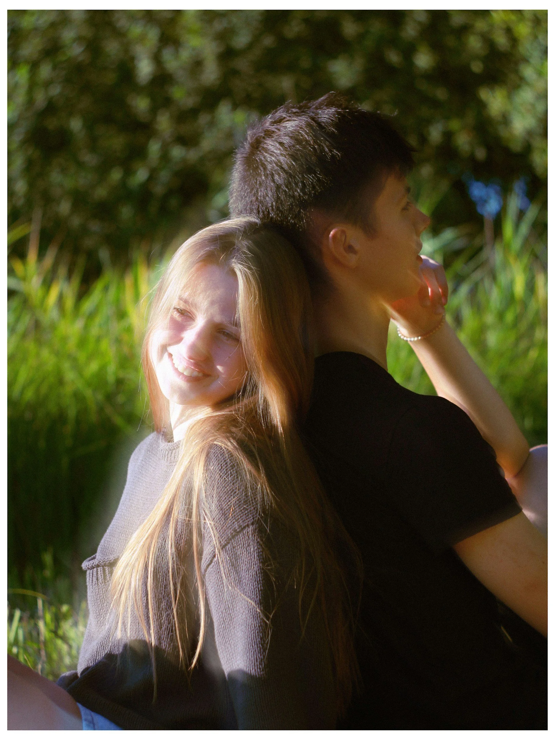 Two teenagers sitting back to back