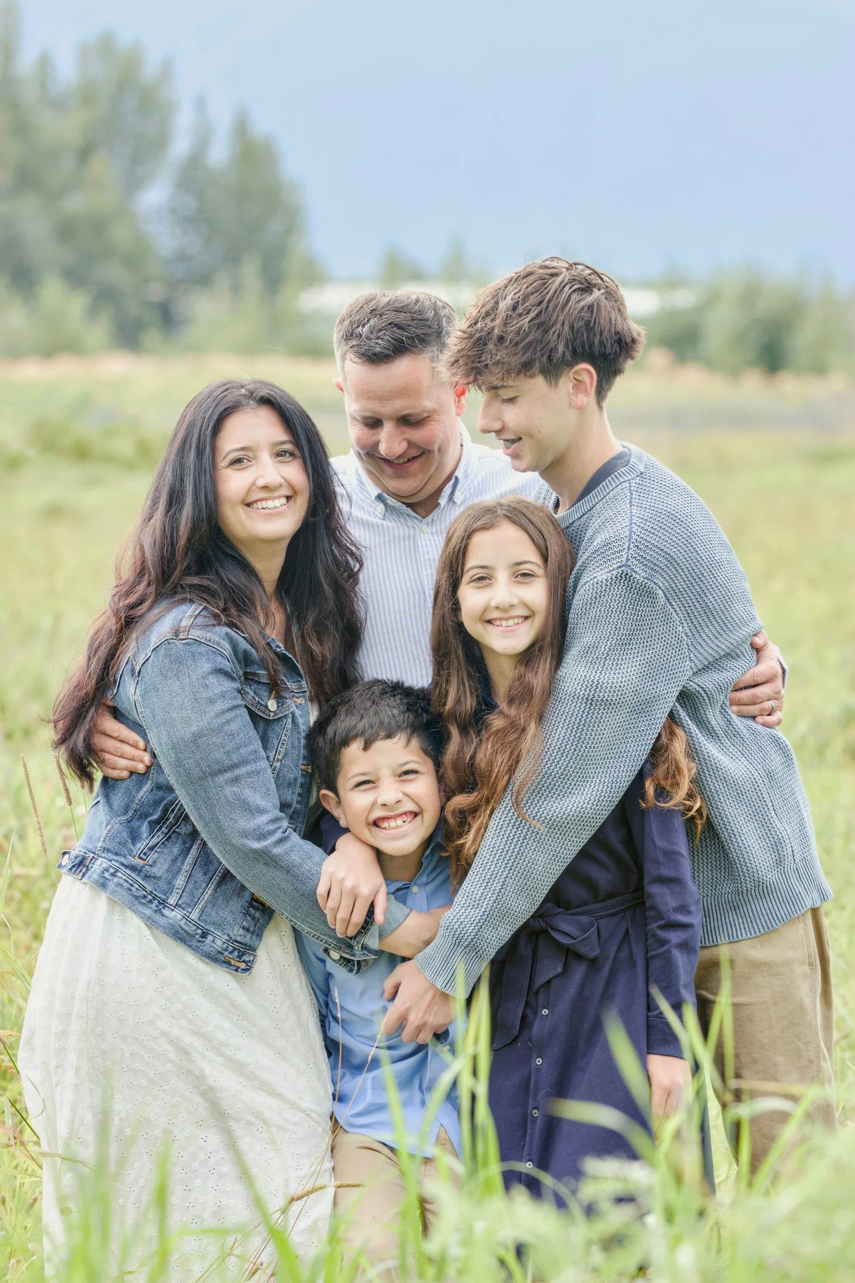 Family of 5 in a field hugging each other