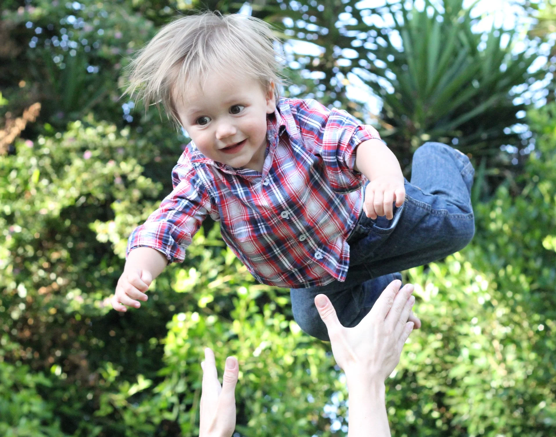 Young blonde boy being thrown into the air