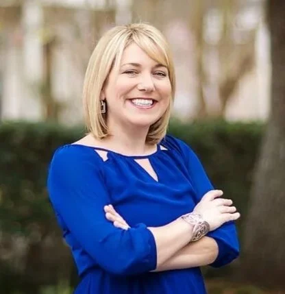 A smiling woman with blonde hair standing with her arms cross - Dr. Rachel Dawkins