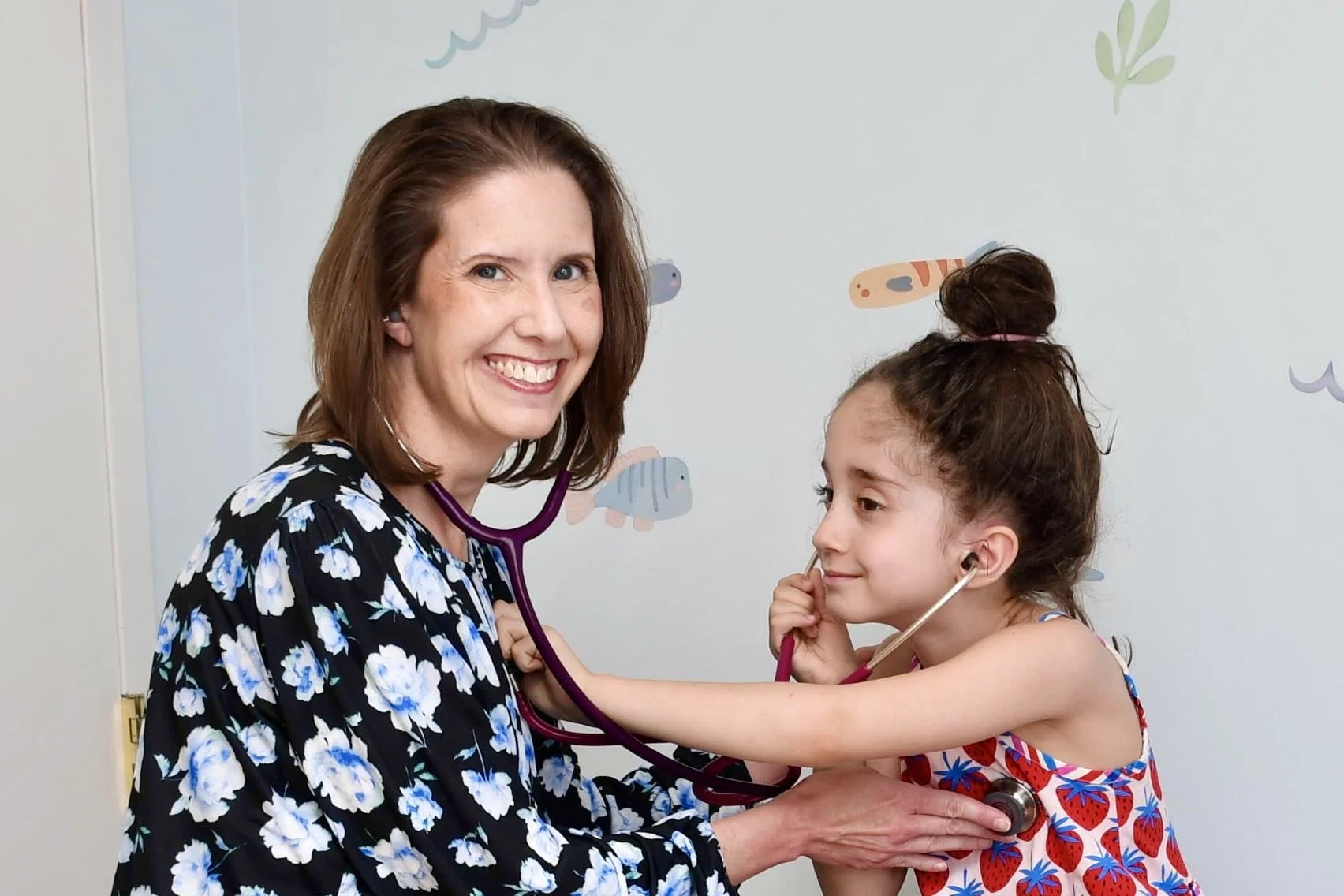 Woman and girl, both with stethoscope listening to each others chest