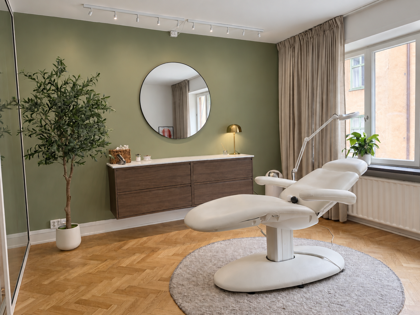 Behandlingsrum på Aesthetic Studio med behandlingsstol, mörk möbel och rund spegel
