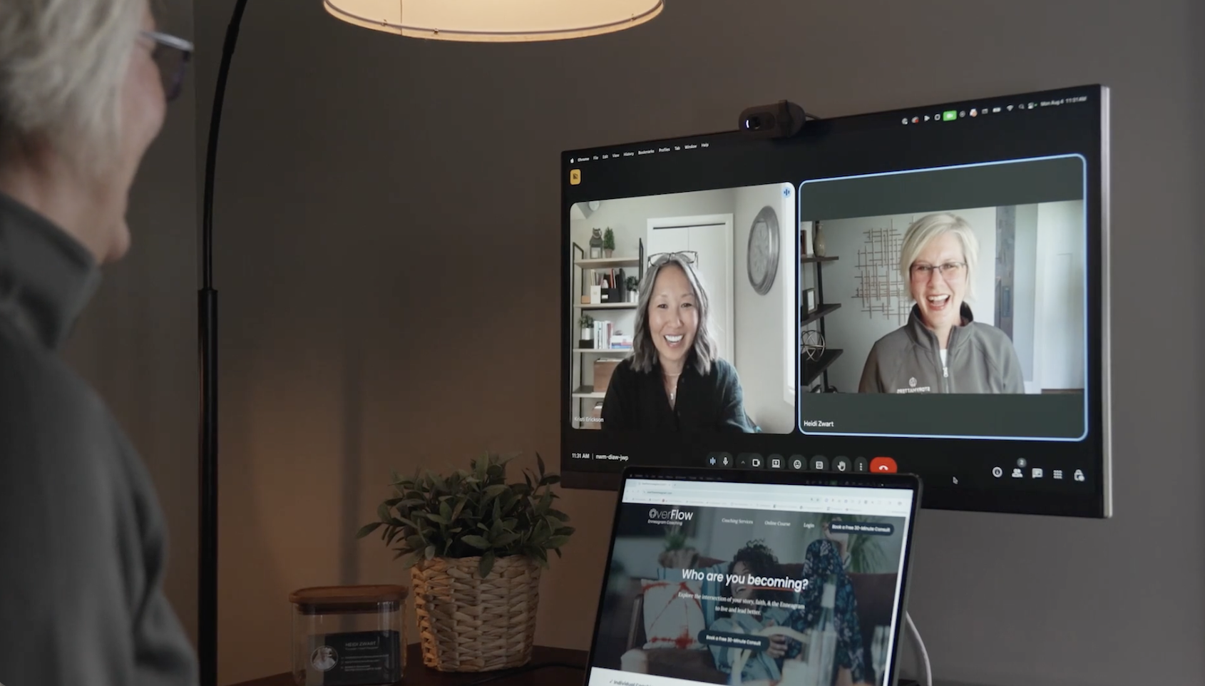 Person participating in a video conference call on a computer monitor, with two women smiling on the screen.