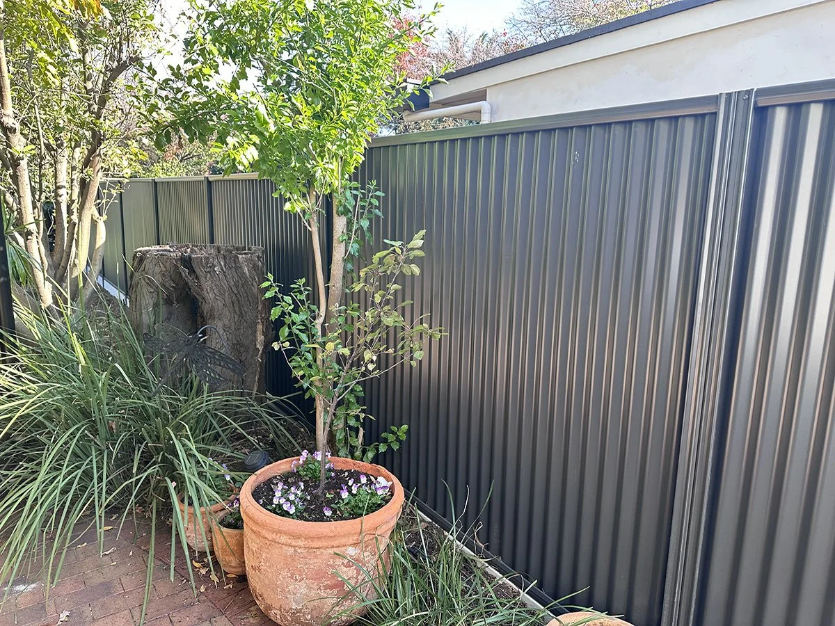 Good Neighbour fence color grey at property and a small tree in pot and bushes
