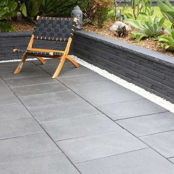 Duostone Retaining Wall Block Graphite in garden and one chair