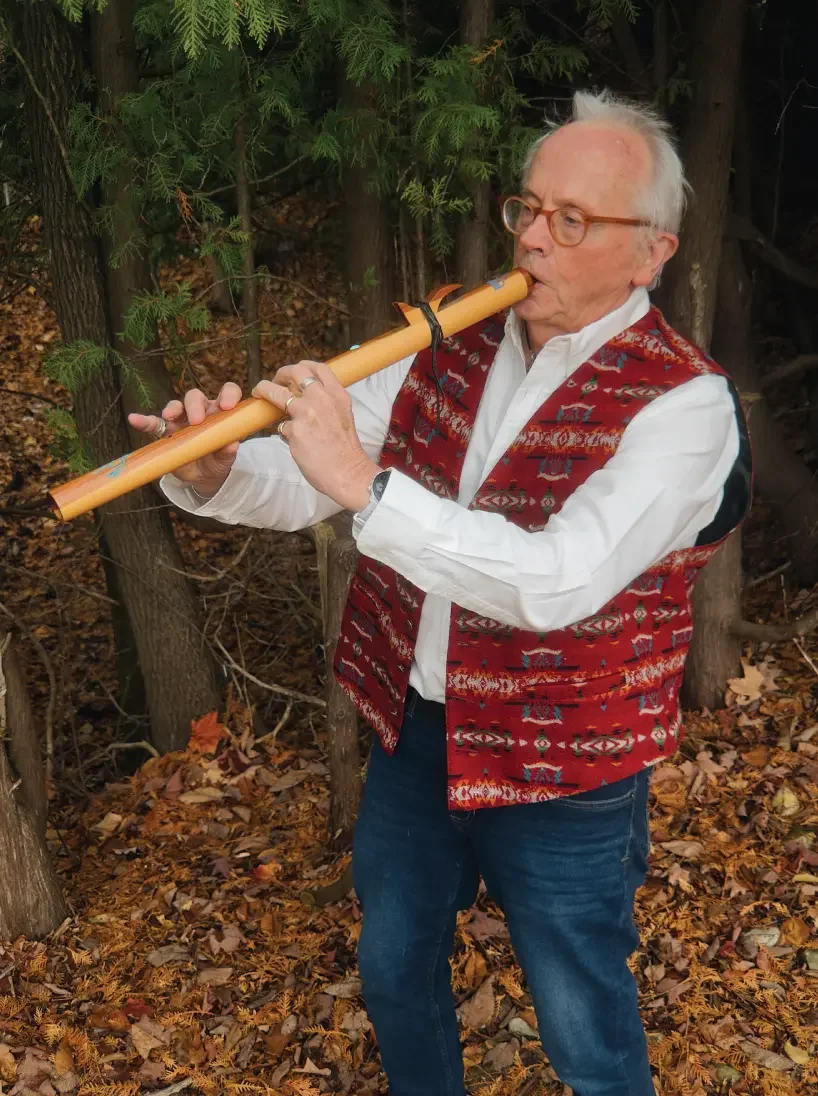Jan Doran playing a wooden flute outdoors
