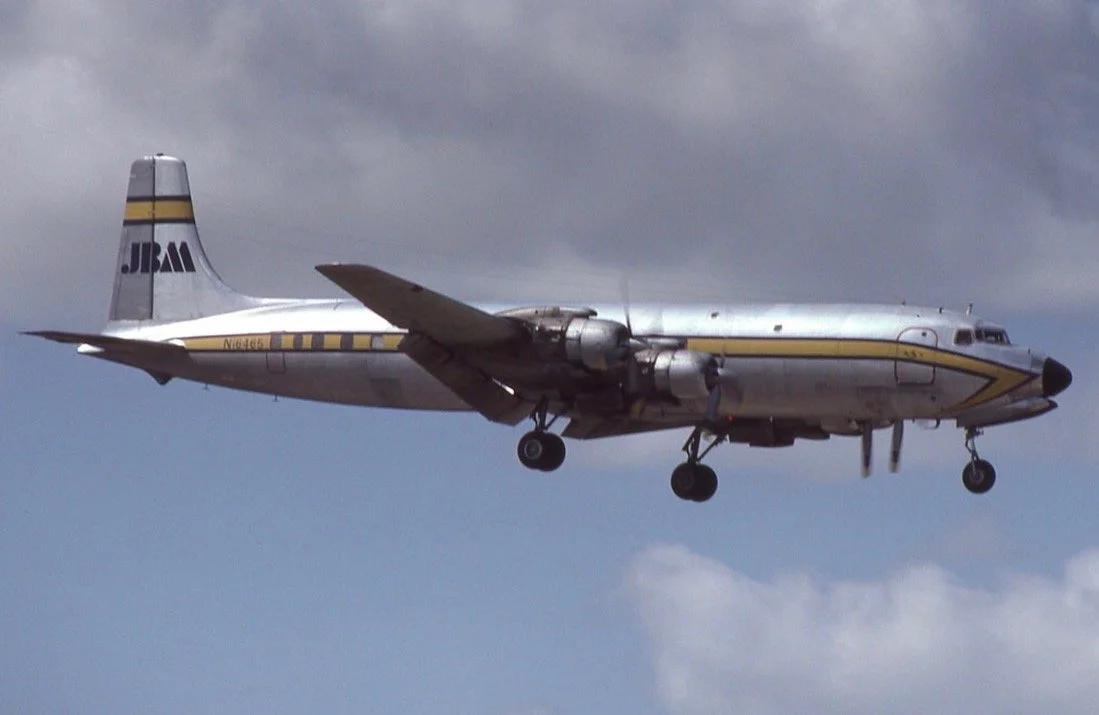 A vintage propeller airplane flying in the sky with a partly cloudy background.