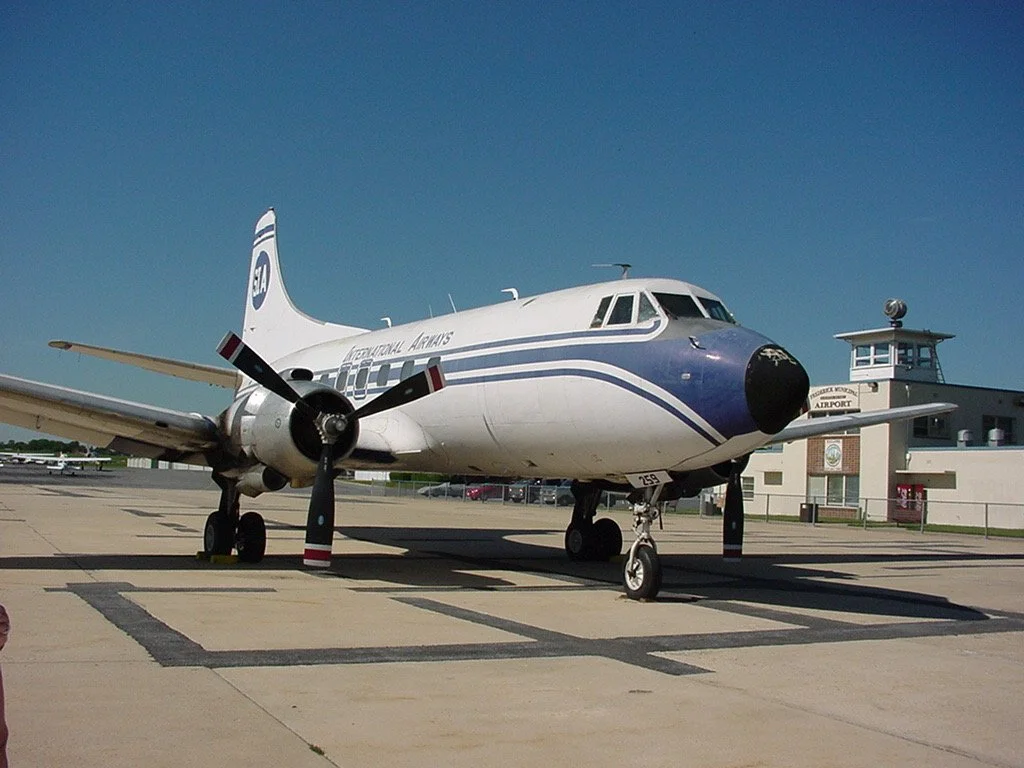 An airplane parked on tarmac at an airport, with a control tower in the background.