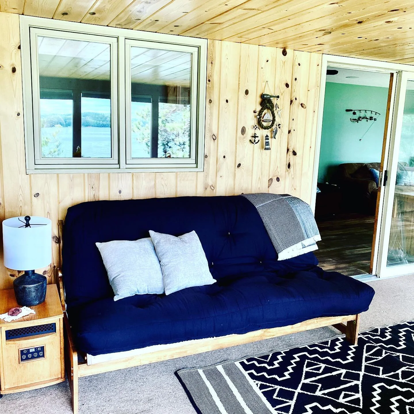 Sunroom with futon seating and bright windows at Island Lake cabin.