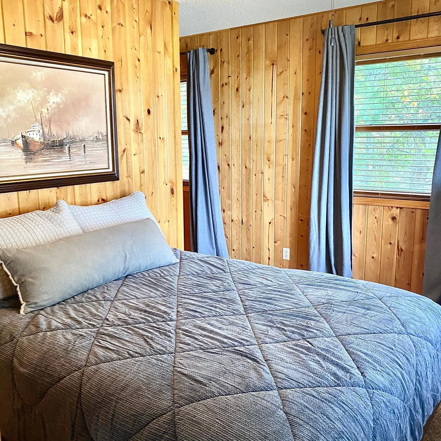 Cozy cabin bedroom with queen bed and lake view window.