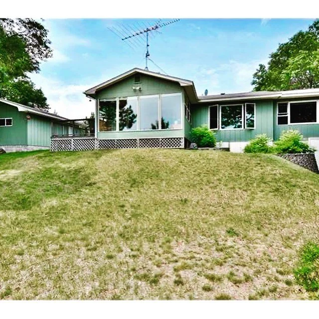 Front view of Island Lake cabin with large yard and green siding.
