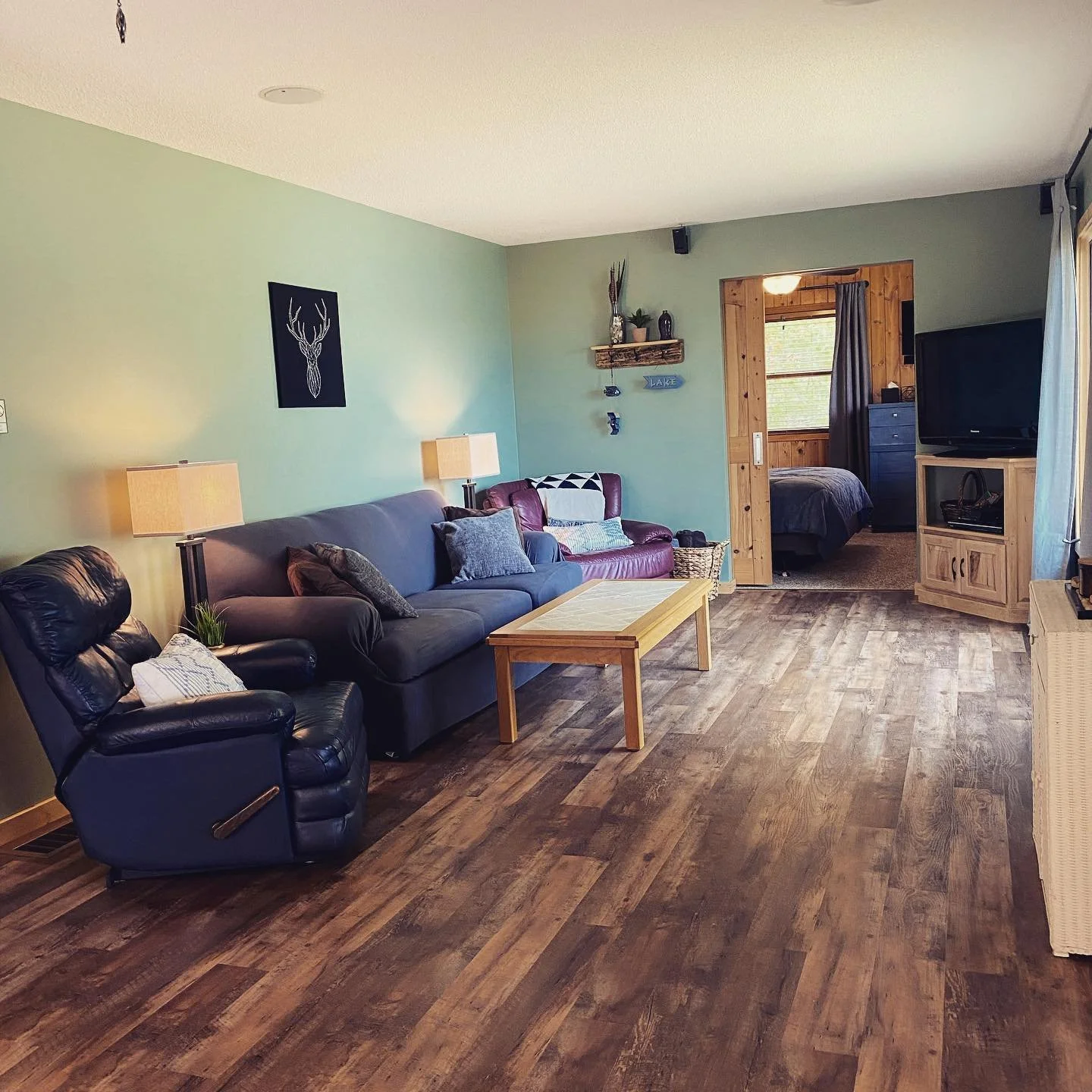 Spacious cabin living room with sofas, large windows, and lake view.