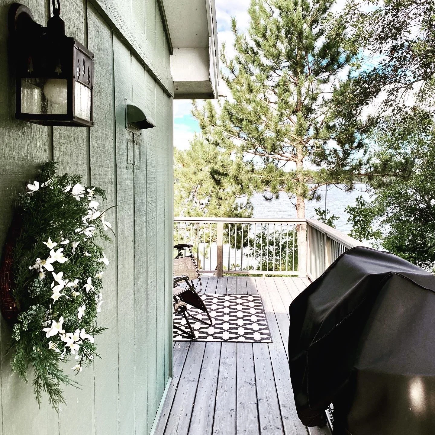 Cabin deck with gas grill, outdoor seating, and lake view at Island Lake.