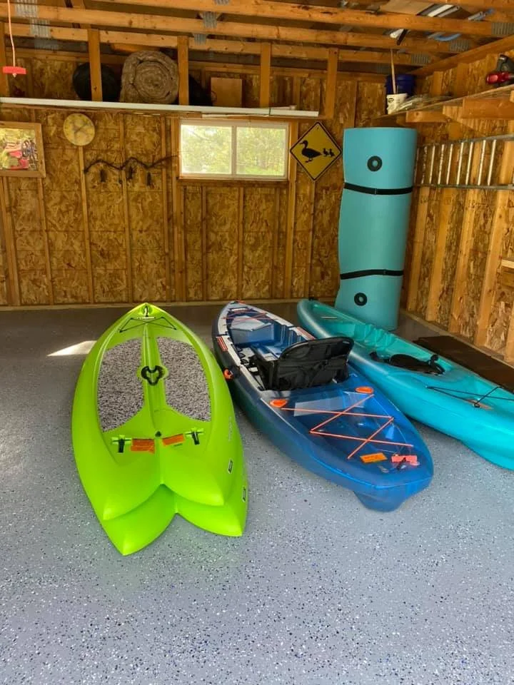 Garage stocked with kayaks, paddle boards, and outdoor adventure gear.