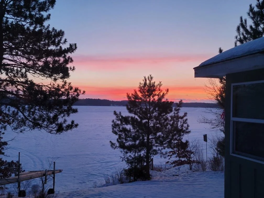 Vibrant winter sunset reflecting on frozen Island Lake near cabin