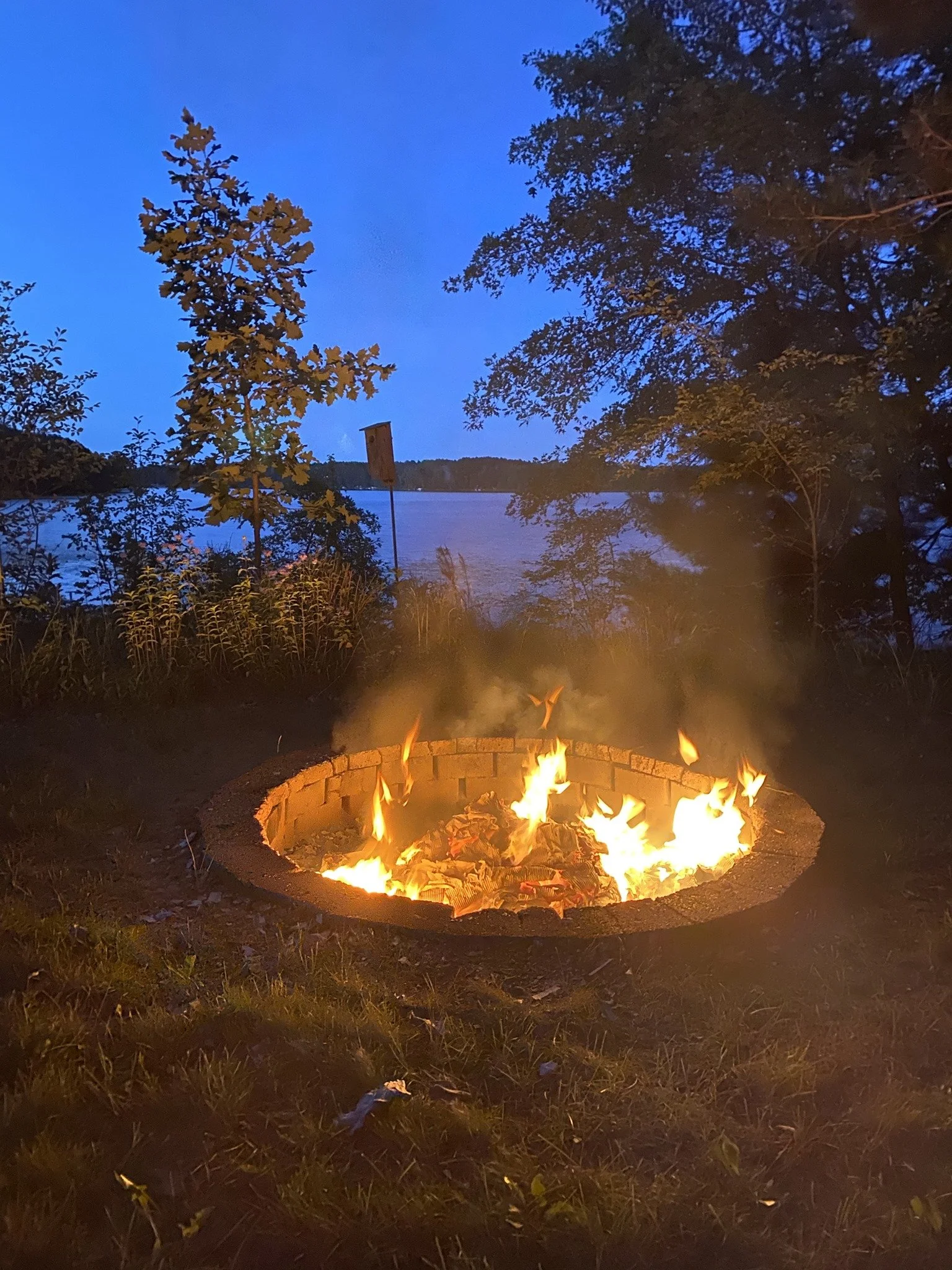 Glowing campfire with Adirondack chairs under a starry night sky at Island Lake cabin.