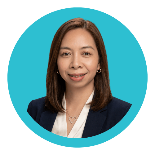 A professional woman with shoulder-length brown hair, wearing a dark blazer and white blouse, smiling at the camera against a blue circular background.