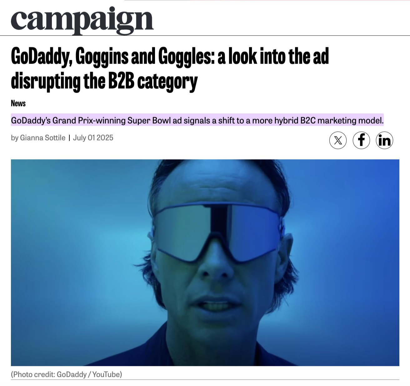 A person wearing reflective goggles, with a blurry blue background, possibly at an event or presentation.