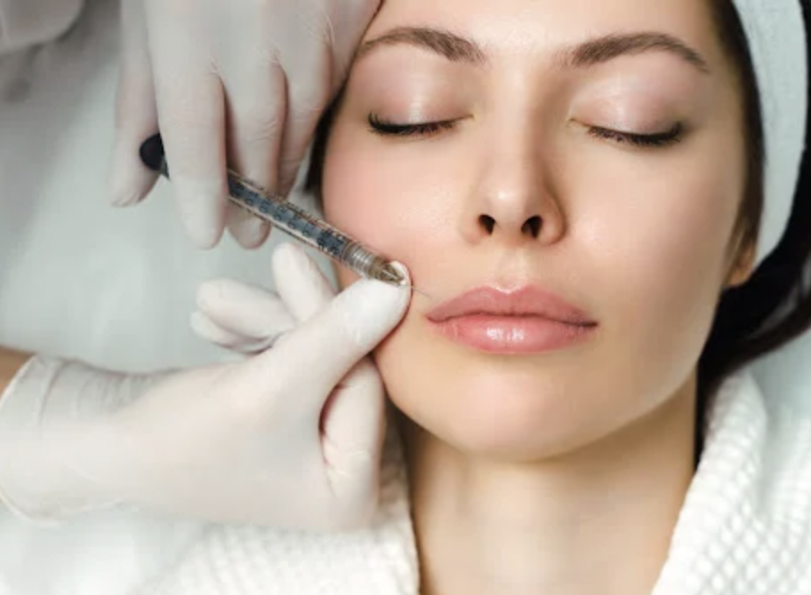 Person receiving a facial treatment with an injection in her cheek from a medical professional wearing gloves.