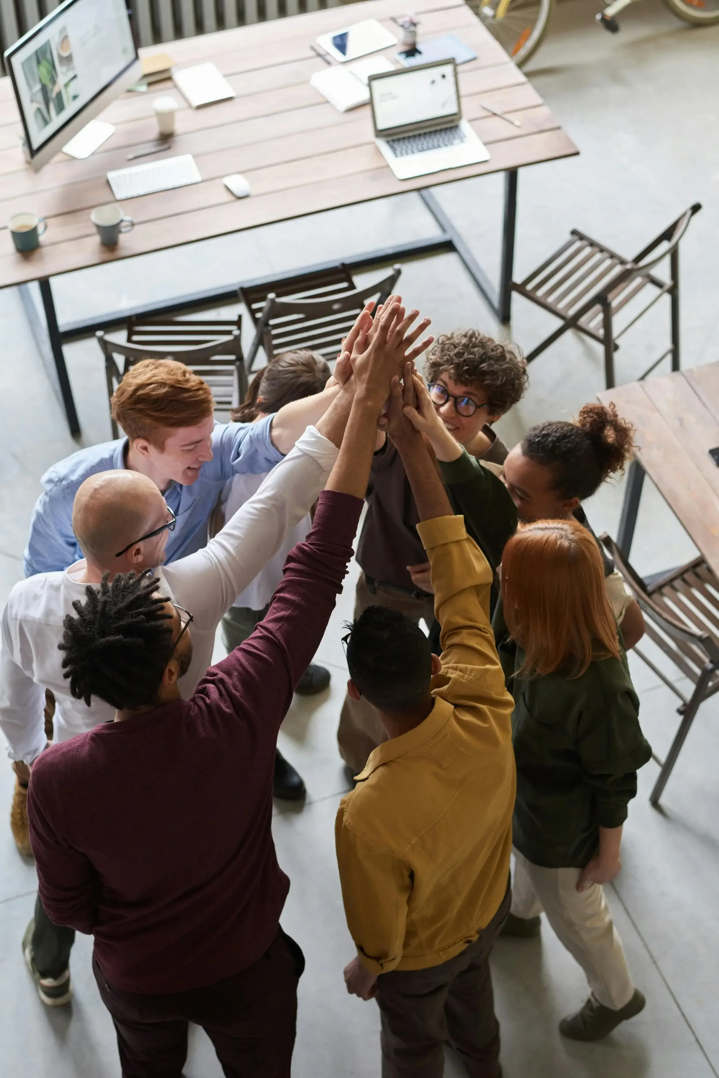 Team members in a circle celebrating and high-fiving.