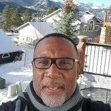 Nimble Advisors client taking a selfie outdoors on a snowy day with houses, trees, and mountains in the background.
