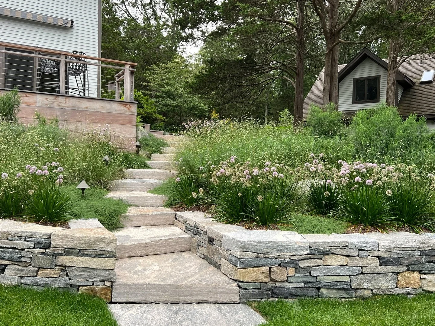 Layered stone, softened edges, and a planting palette that moves with the breeze
