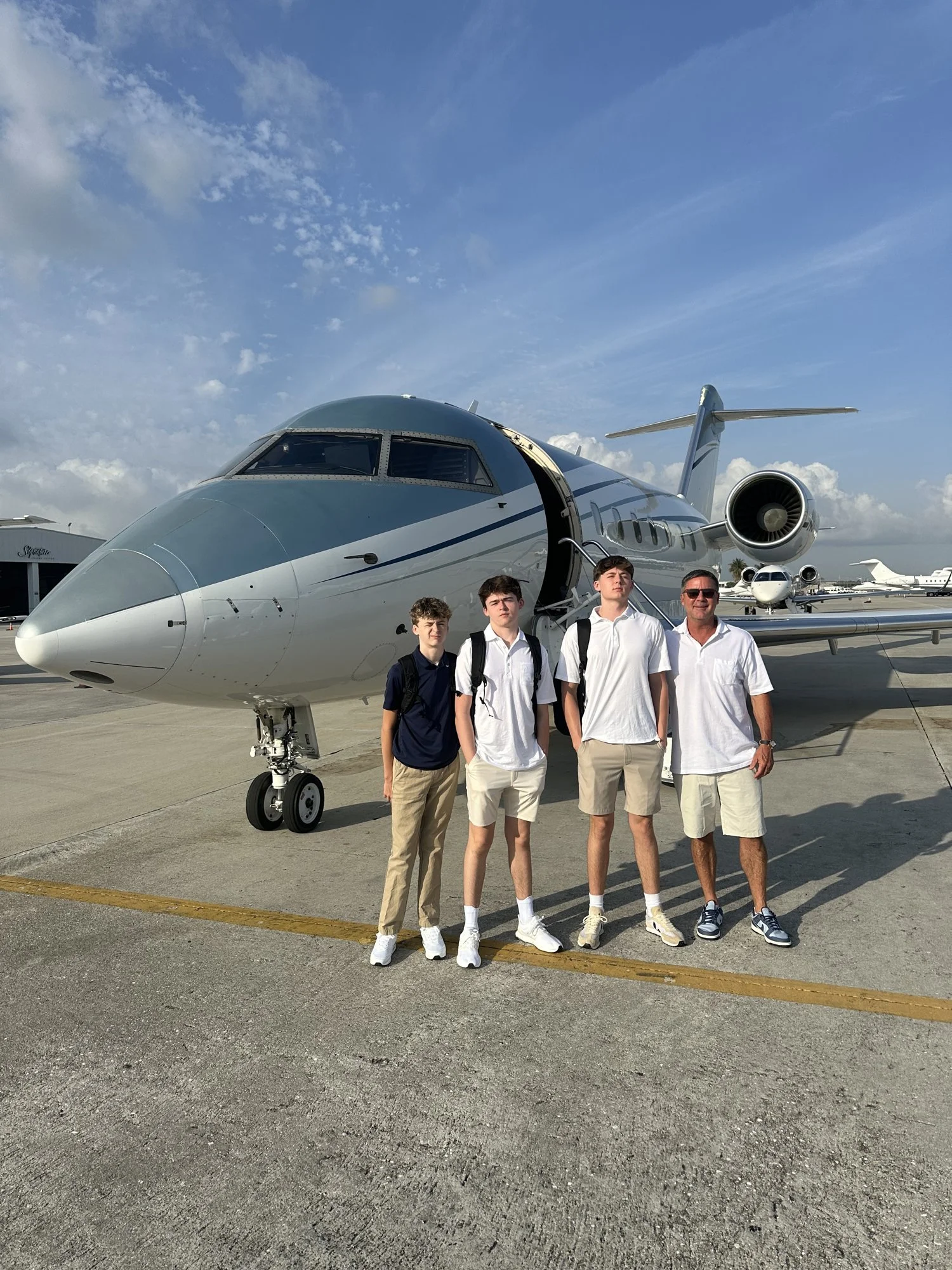 Paul Gravette with three young men in front of a private jet.