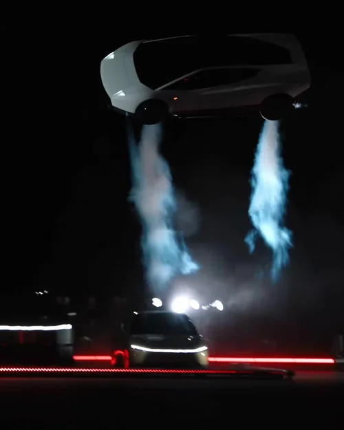Still from the video: a car flying above a dark stage on twin jets of vapor. Watch it on X.